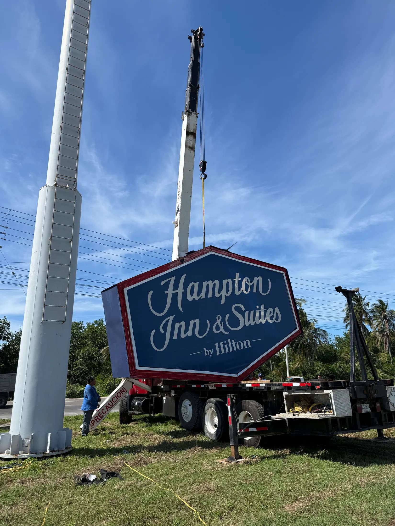 Montaje con grúa de un letrero hexagonal de Hampton Inn & Suites sobre poste